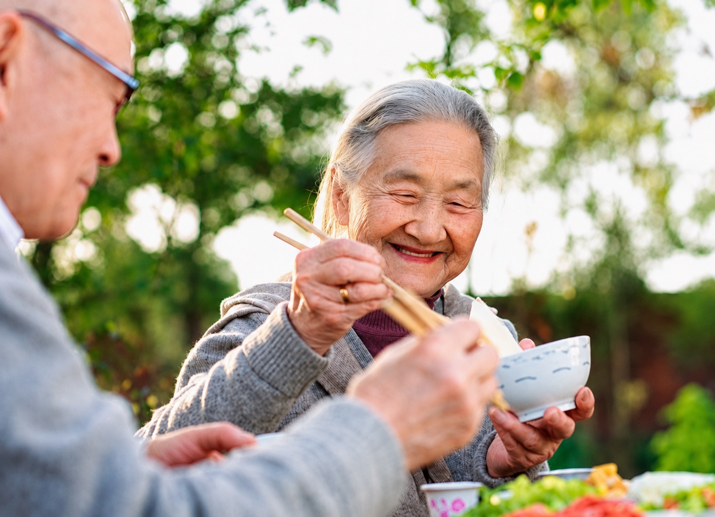 A grandmother enjoying a home-style meal outdoors with family